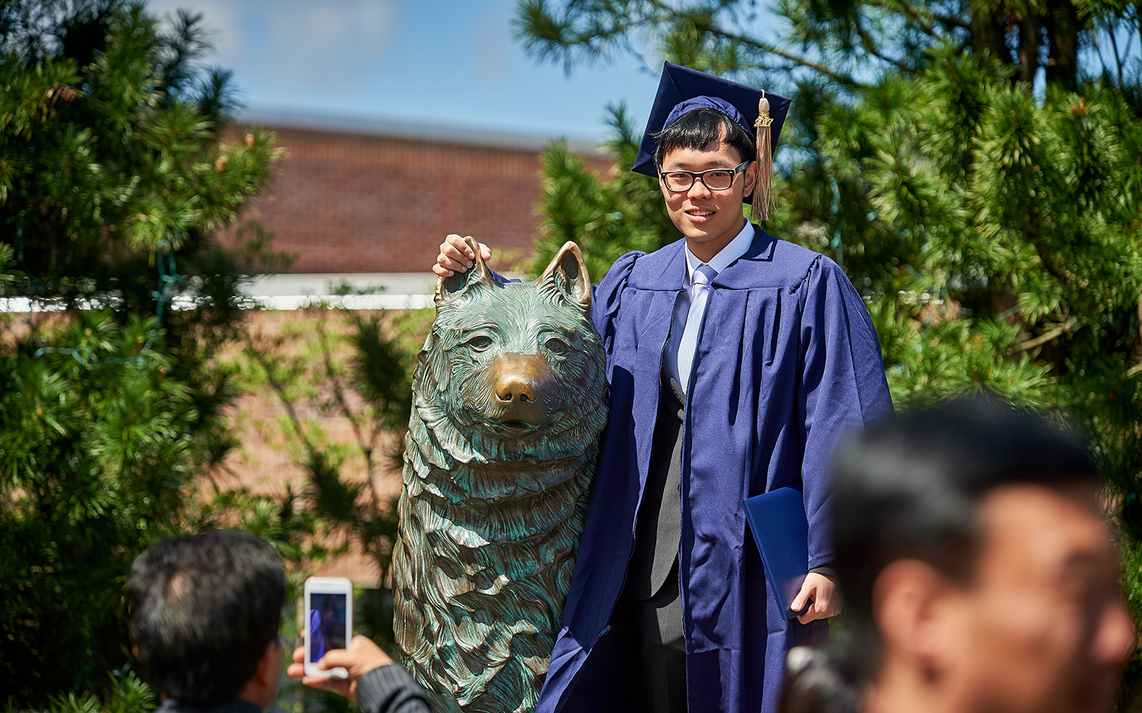 Bo Ni '17 (BUS) poses for a photo with the husky statue following the School of Business Commencement ceremony on May 7, 2017. (Peter Morenus/UConn Photo)
