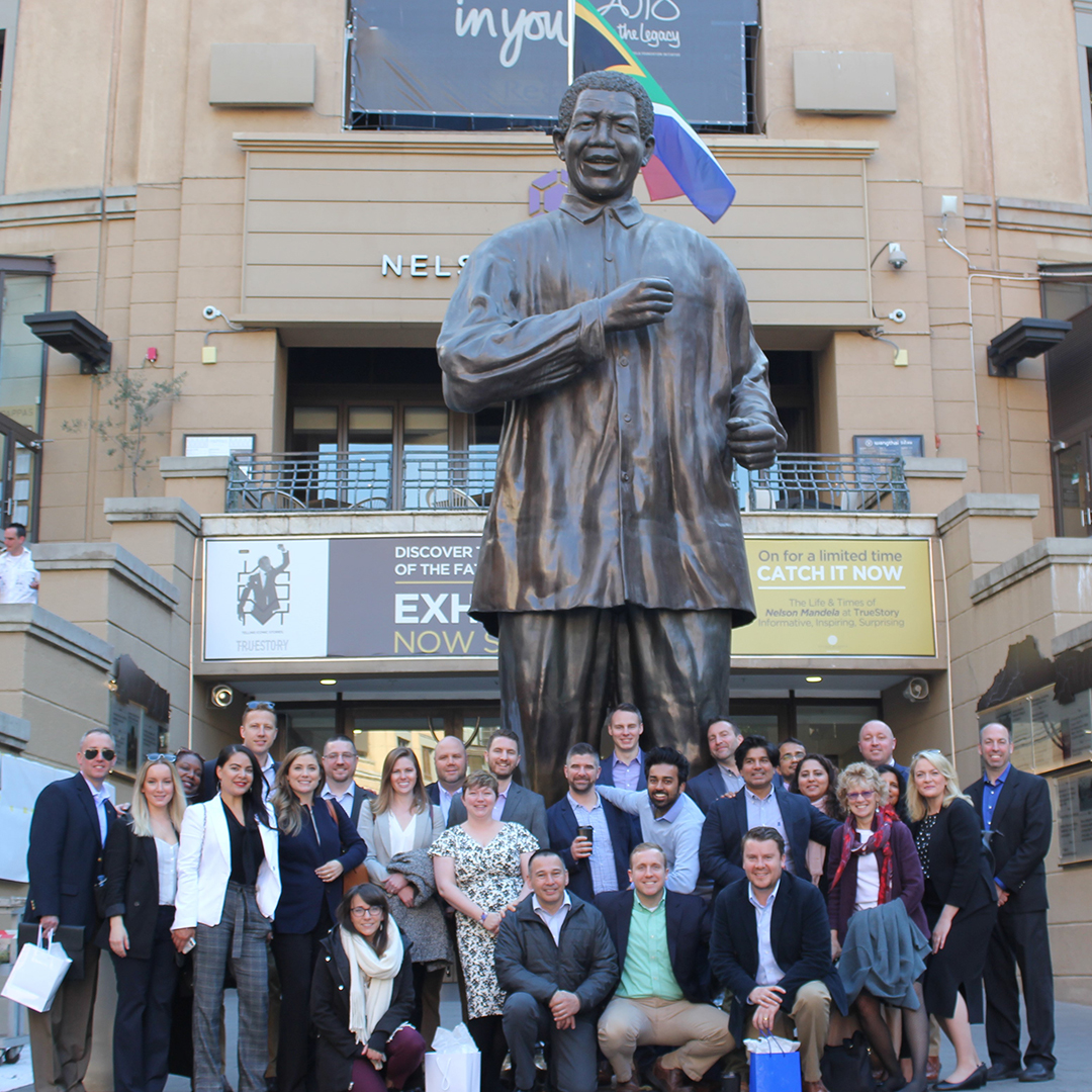 EMBA Class of 2020 posing with statue of Nelson Mandela in Mandela Square in Johannesburg.