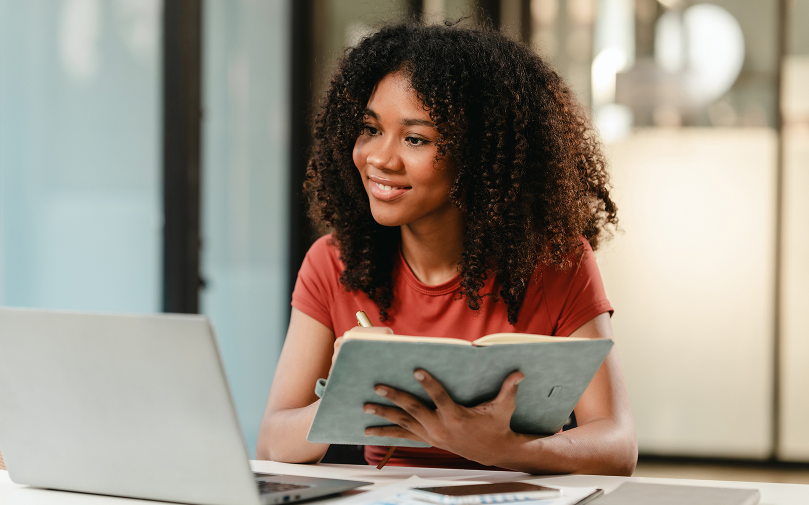 UConn School of Business Online MBA program, Student taking class on a laptop computer and taking notes.