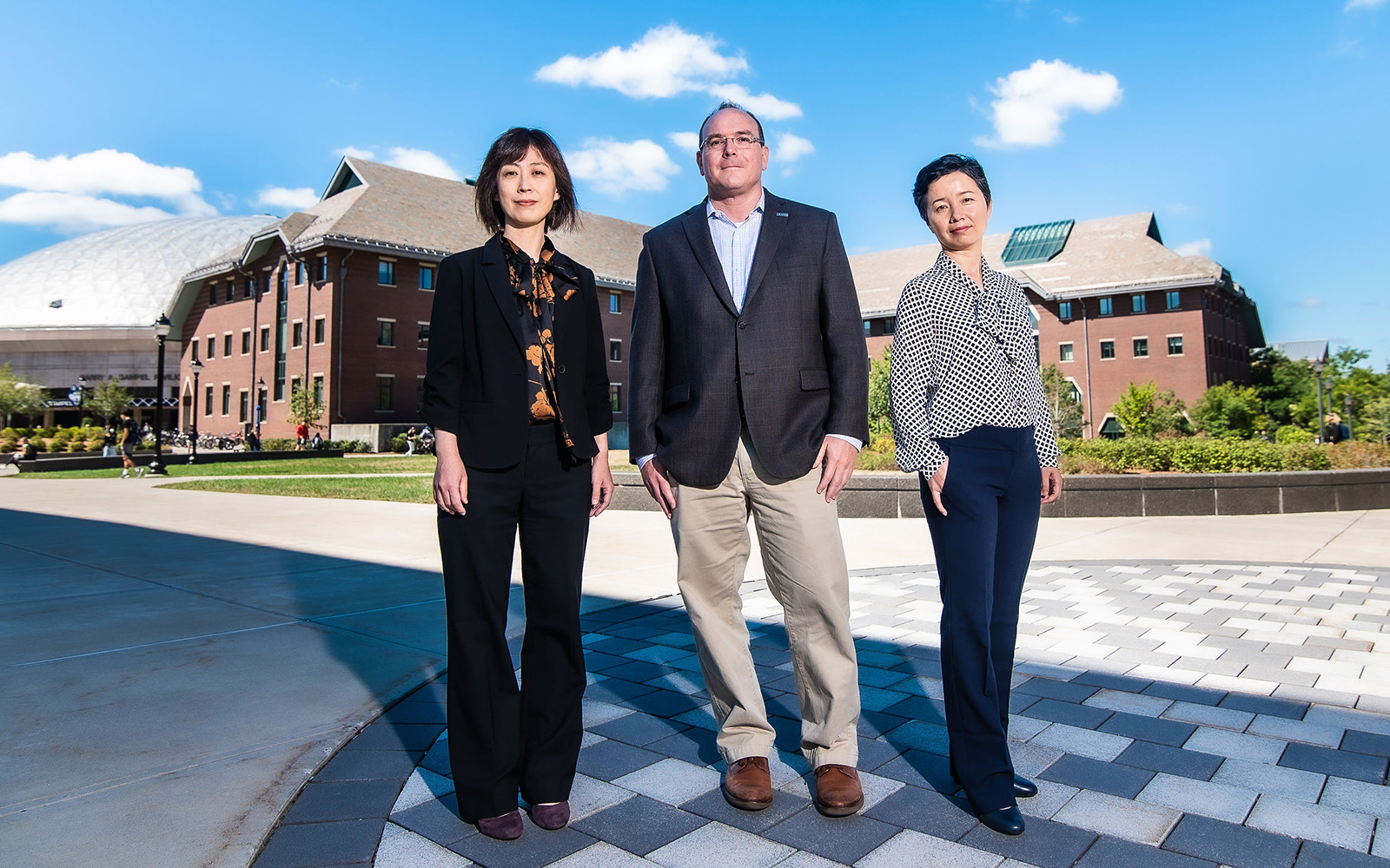 Professors XinXin Li Bob Day and Cuihong Li outside the School of Business Storrs campus on a sunny day