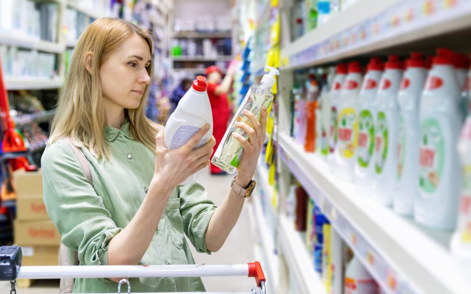 Female shopper in the aisle of a grocery store comparing products.
