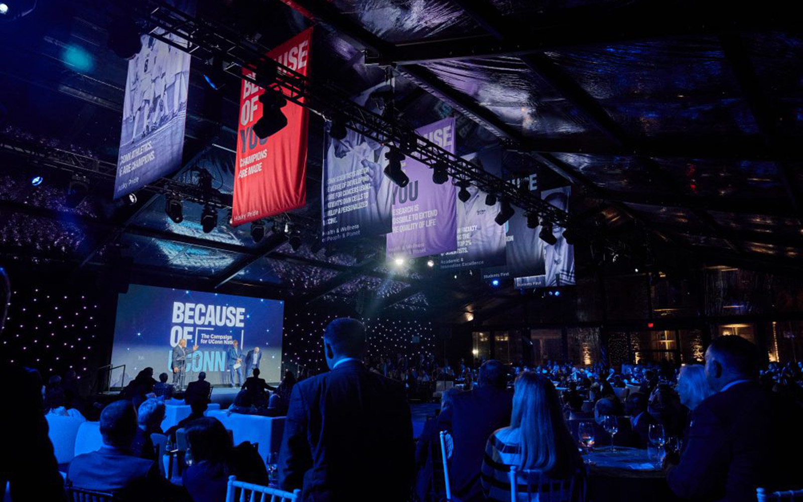 Dramatic lighting of banners hanging over a crowd.
