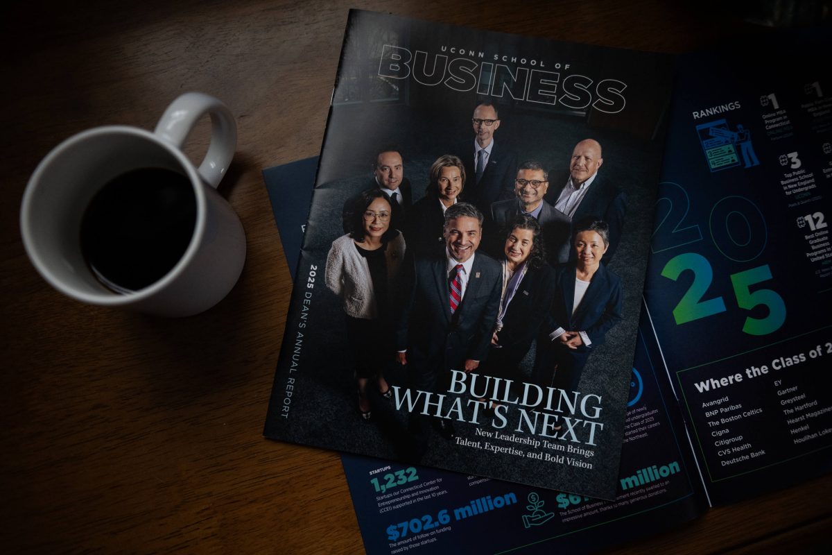Photo of Dean's Report on top of a table closed with a coffee cup next to it.