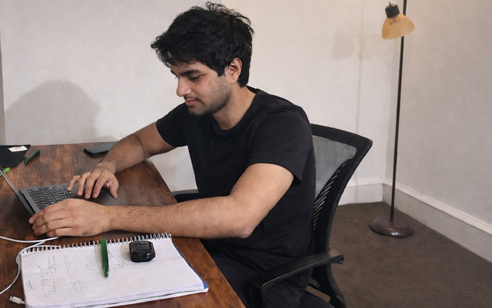 Uday Pandey, working on a laptop at a desk with a notebook beside him.