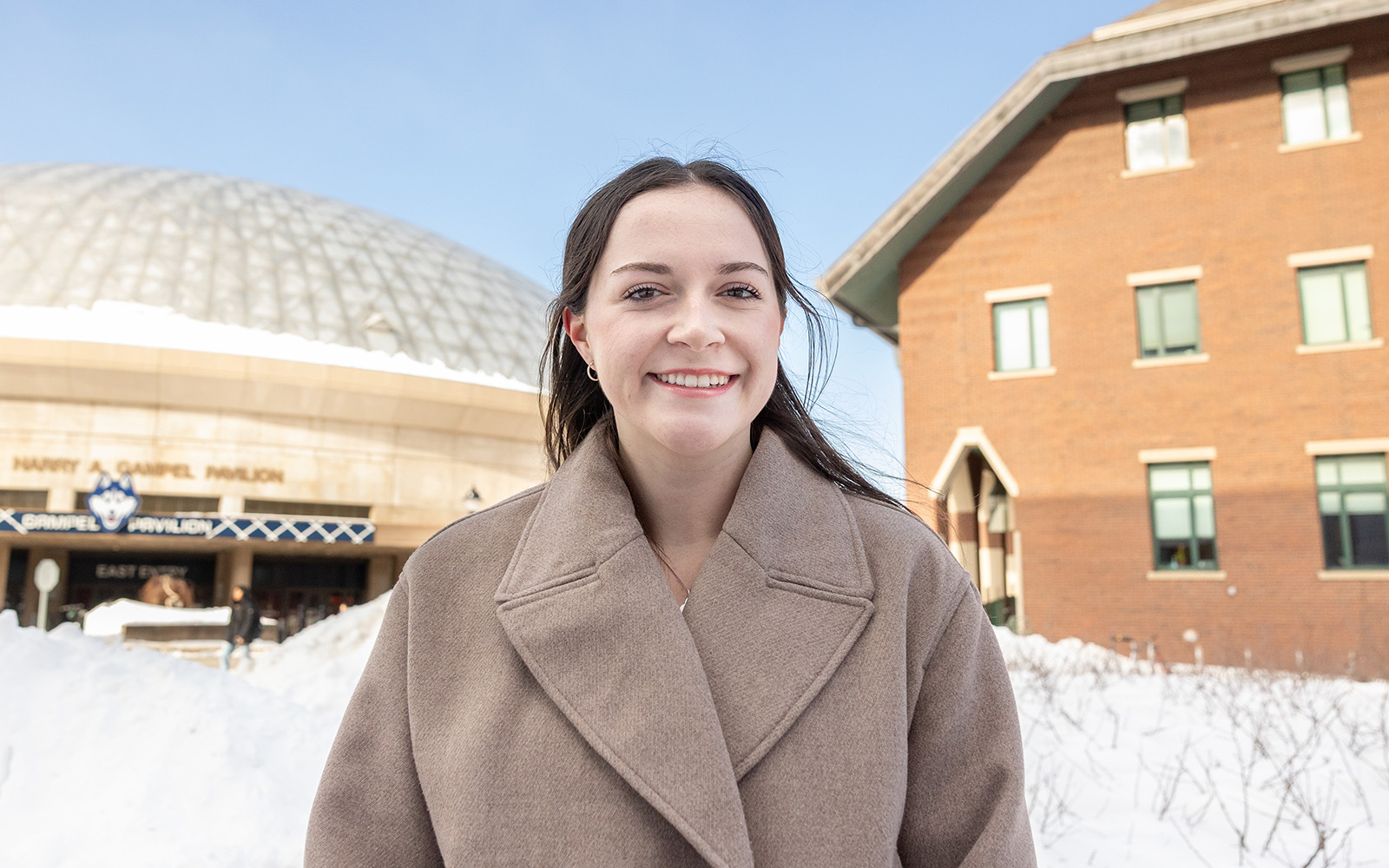 A young woman poses for a portrait photo with two large buildings in the background.