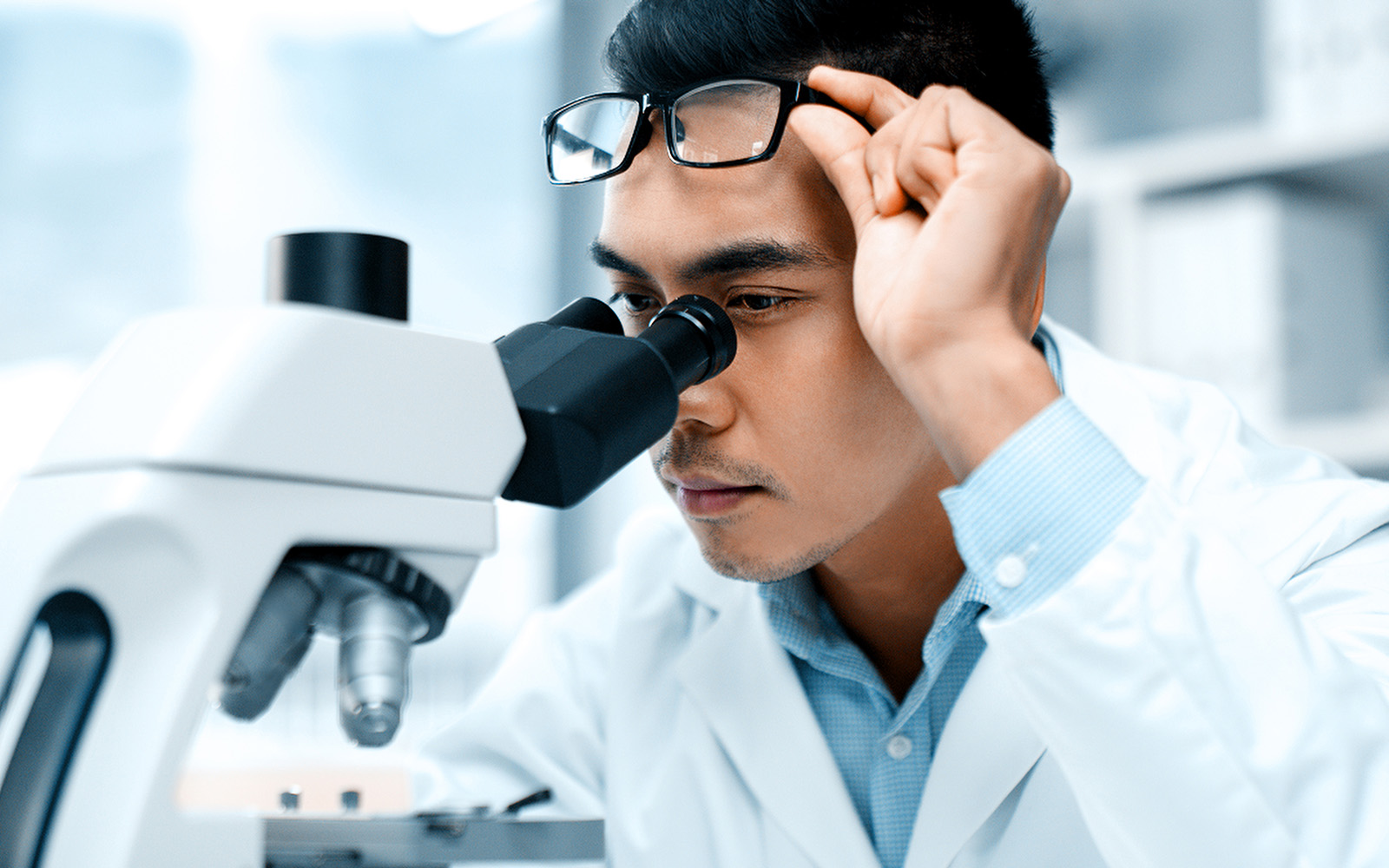 Cropped shot of a focused young male scientist looking through a microscope while working in his laboratory