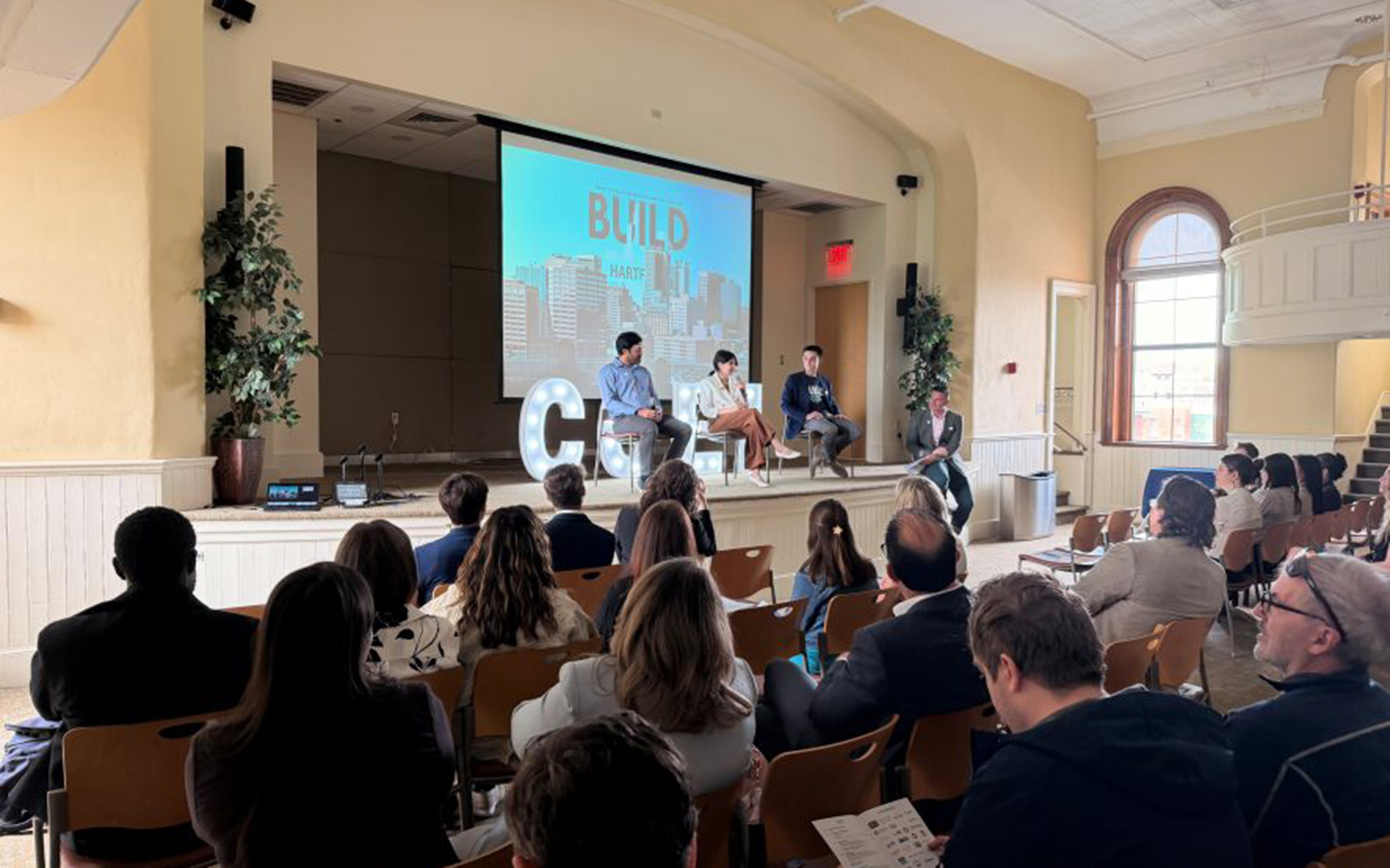 Three people on stage presenting to a crowd