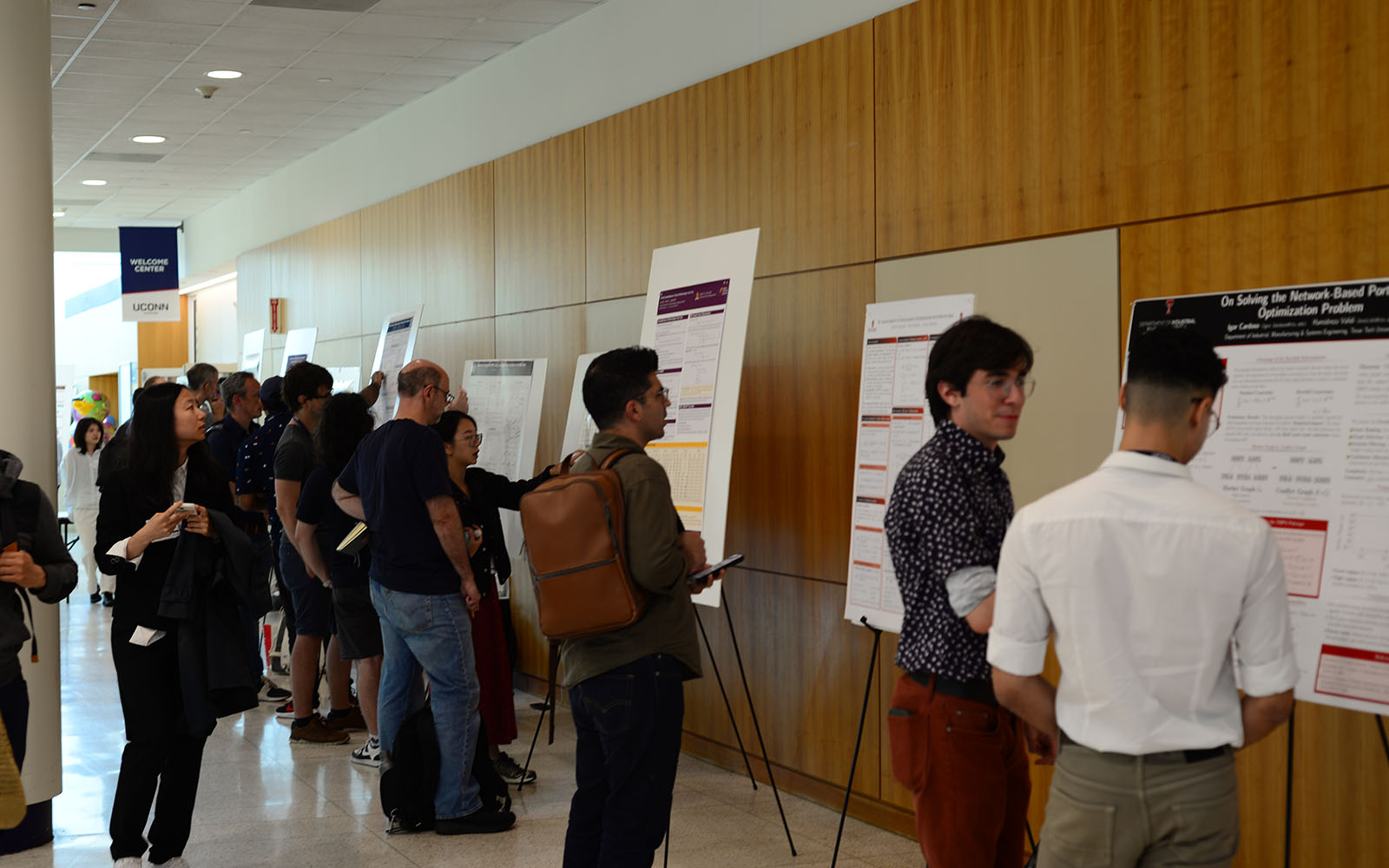 A crowd of people look at research posters.