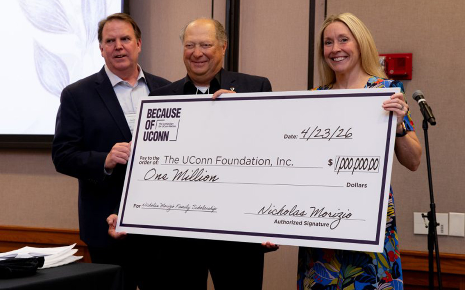 Three people hold a large novelty check for $1 million.