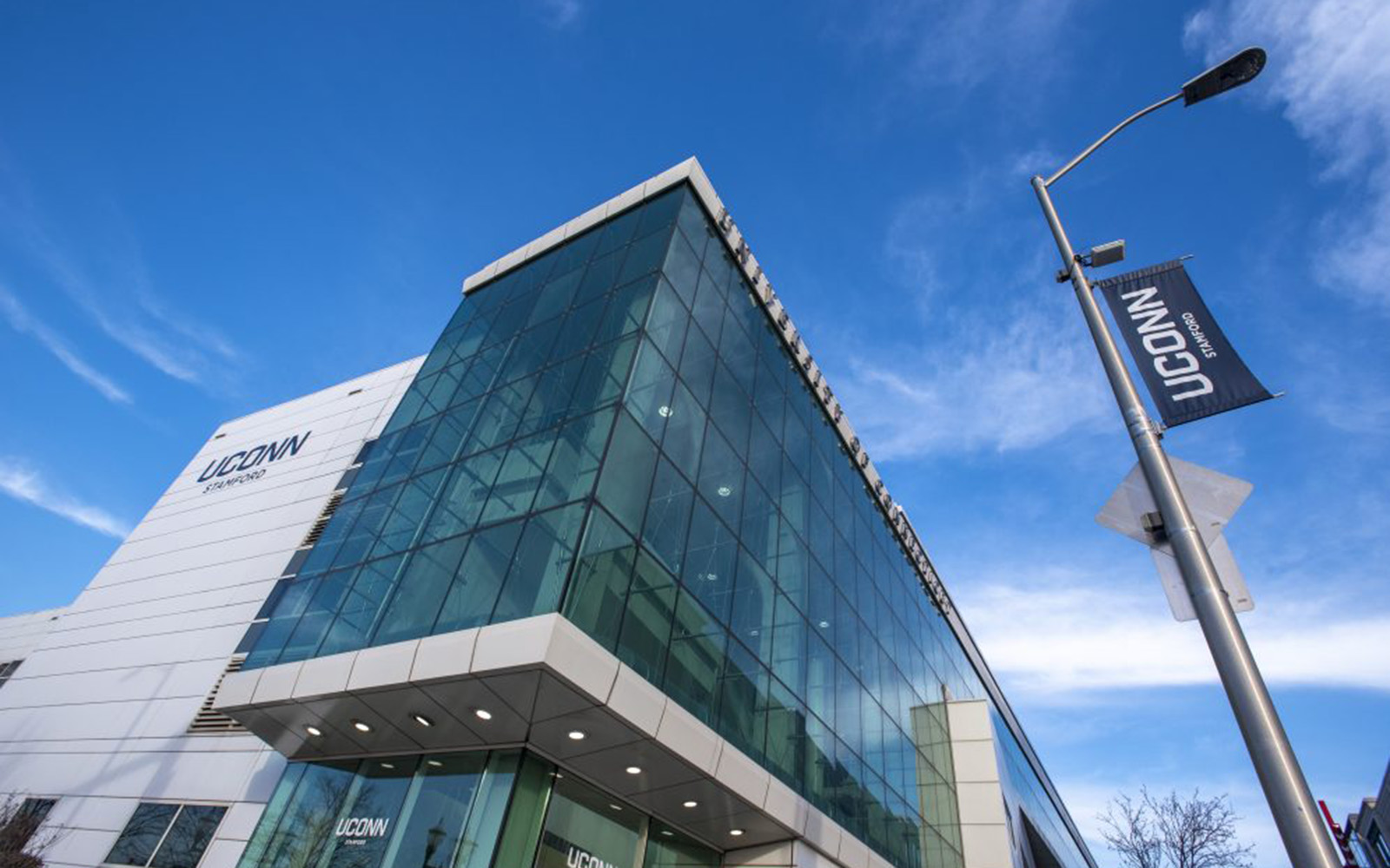 An exterior view of a glass-paneled building in front of a blue sky on the UConn Stamford campus.